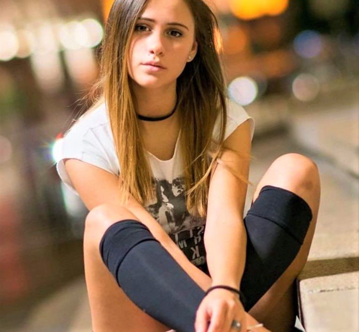 Sexy Maria Bakalova sitting on steps outdoor.
