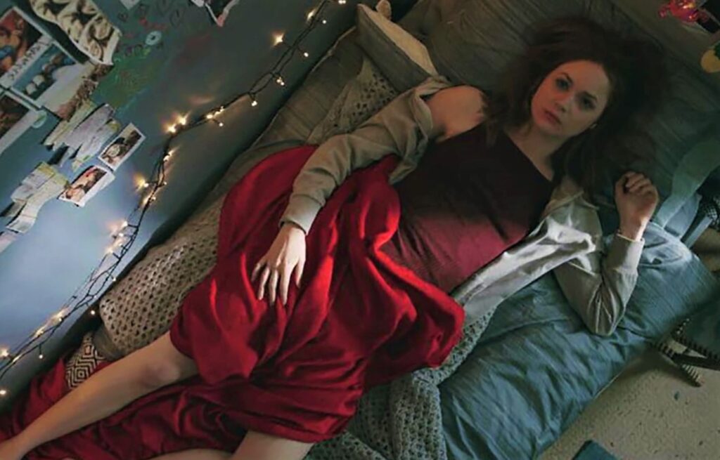 Karen Gillan looking sexy while lying in bed in 2018 film The Party's Just Beginning.